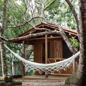 a hammock in front of a cabin in the woods at Sitio Namaste in Itacaré