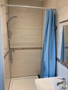 a shower with a blue shower curtain next to a sink at Apart-Hotel Rheinischer Hof Dormagen in Dormagen