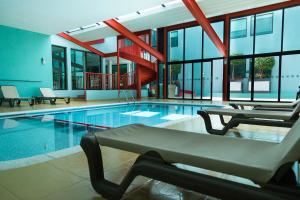 a swimming pool with chairs and a staircase in a building at Excellence Express & Suites in San Juan del Río