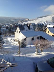 une maison avec de la neige au sol à côté dans l'établissement Fewo-Michi, à Kurort Oberwiesenthal