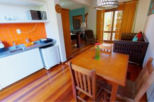 cocina y comedor con mesa de madera y sillas en Pousada Vila Boa Vida, en Bombinhas