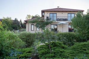 a house with a balcony and an umbrella at Azur Villa in Balatonalmádi