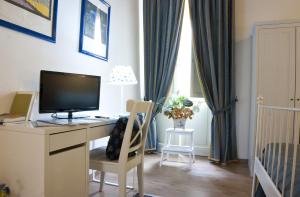 a room with a desk with a television and a crib at La Dimora Di Odisseo in Trapani