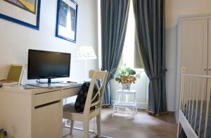 a room with a desk with a television and a crib at La Dimora Di Odisseo in Trapani