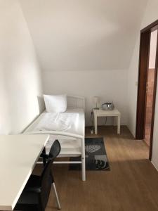 a bedroom with a white bed and a table at Pension ,,Vier Tore'' in Neubrandenburg