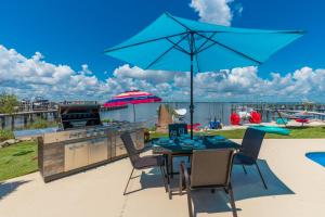 un patio con parrilla y una mesa con sombrilla azul en Aquatopia South, en Stuart 41 fotos más