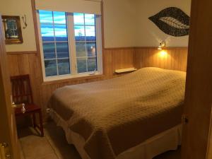 a bedroom with a bed and a window at Eyjasol Cottages in Reykholt