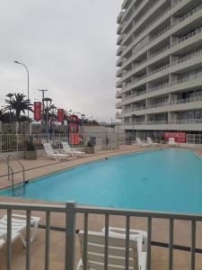a swimming pool with chairs and a large building at Departamentos La Serena Vista in La Serena
