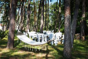 a hammock in the grass next to tables and trees at Willa Alexander Resort & SPA - caloroczny kryty BASEN in Mielno +23 photos