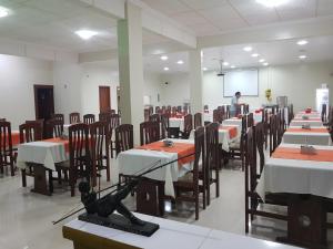 a man standing in a room with tables and chairs at Hotel Takana in Tabatinga