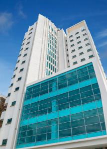 巴蘭基亞的住宿－Hotel Dorado Plaza Alto Prado，一座高大的白色建筑,设有蓝色的玻璃窗