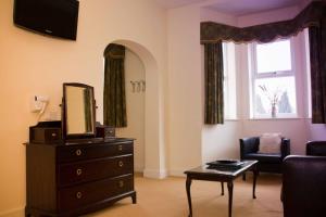 a living room with a dresser and a mirror at Beverley Hotel in Walsall