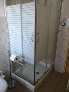 eine Dusche mit einer Glastür und einer Rolle Toilettenpapier in der Unterkunft S'arrulloni in Cagliari