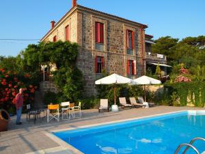 a woman standing near a swimming pool in front of a building at Molyvos Manor in Mythimna