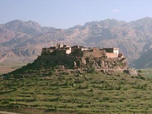 Tizourgane Kasbah في Tiguissas: قلعة على تلة مع جبال في الخلفية