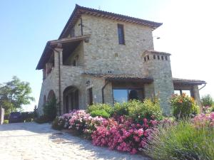 托迪Agriturismo La Torraccia的一座大石头房子前面有鲜花 更多37张照片