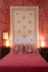 1 cama con edredón rojo y 2 lámparas en Casa Rural Los Pedregales, en Carenas