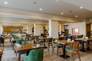 a restaurant with wooden tables and green chairs at Olivia Palm Hotel in Kyrenia