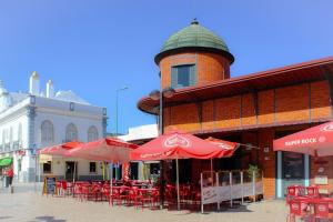 a building with red tables and chairs and umbrellas at BaixaMar Apartments in Olhão