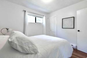 a white bedroom with a white bed and a window at LOVELY HOME 10 MINUTES TO DOWNTOWN !!! in Victoria