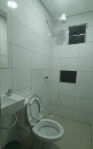 a white bathroom with a toilet and a sink at Royal Hotel in Sao Paulo