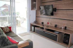 een woonkamer met een flatscreen-tv aan de muur bij Luxo e Conforto em Jurerê in Florianópolis