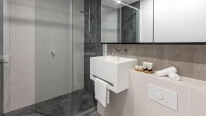 a white bathroom with a sink and a shower at Avani Melbourne Central Residences in Melbourne