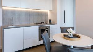 a kitchen with a table and a sink and a stove at Avani Melbourne Central Residences in Melbourne