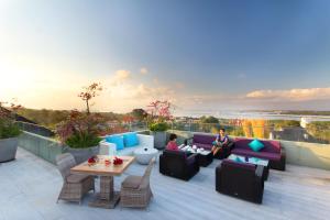 a patio with couches and tables on a roof at Amaroossa Suite Bali in Nusa Dua