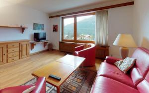 ein Wohnzimmer mit einem roten Sofa und einem Tisch in der Unterkunft Suot Brattas 21 in St. Moritz