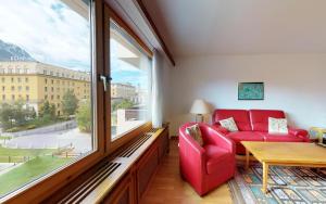 ein Wohnzimmer mit einem roten Sofa und einem großen Fenster in der Unterkunft Suot Brattas 21 in St. Moritz