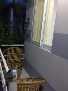 a balcony with two wicker chairs and a window at Nostress Guest House in Mui Ne