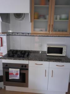 uma cozinha com um fogão e um micro-ondas em Estrela do Mar - 100m da praia em Peniche