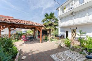 a patio with a wooden pergola next to a building at Apartment and Room Ilija in Tribunj