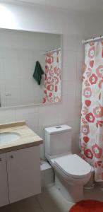 y baño con aseo, lavamanos y cortina de ducha. en Departamentos La Serena Vista en La Serena