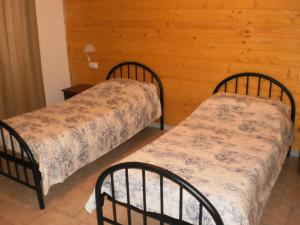 two beds in a room with a wooden wall at Cantuccio in Cengio