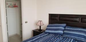 Un dormitorio con una cama y una lámpara en una mesita de noche. en Departamentos La Serena Vista, en La Serena 19 fotos más