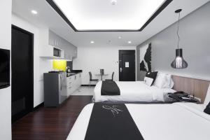 Y2 Residence Hotel Managed by HII في مانيلا: غرفة فندقية بسريرين ومطبخ