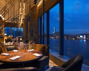 a dining room table with a balcony overlooking the ocean at Hyatt Centric Victoria Harbour in Hong Kong