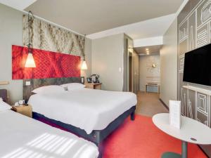 a hotel room with two beds and a flat screen tv at ibis Saint Germain en Laye Centre in Saint-Germain-en-Laye