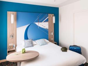 una camera con un grande letto con una parete blu di ibis Styles St Gilles Croix de Vie centre-ville a Saint-Gilles-Croix-de-Vie