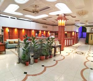 a lobby with potted plants on the floor at Almudawah Hotel in Ţurayf