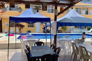 dois guarda-sóis azuis sobre mesas e cadeiras ao lado de uma piscina em HOTEL SUNSHINE AIRE ACND y WIFI ZONE em Tonsupa