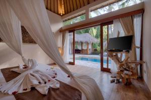 a bedroom with a bed and a tv and a pool at Kutus Kutus Mas Ubud Villa in Ubud