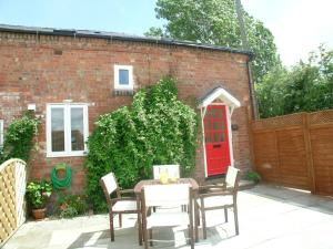 a patio with a table and chairs and a red door at Juliet Cottage HOT TUB Sleeps 3 Singles or Double in Stratford-upon-Avon