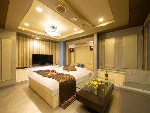 ein Schlafzimmer mit einem Bett, einem TV und einem Sofa in der Unterkunft Hotel Gee (Adult Only) in Sakai