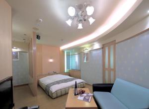 a bedroom with a bed and a couch and a television at Hotel Mio City (Adult Only) in Yokkaichi