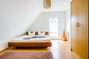 a white bedroom with a bed and a window at Cosy Family Home in Tuningen