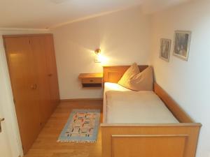 a small bedroom with a bed with a wooden headboard at Rooftop Apartment in Bad Hofgastein