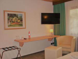 Zimmer mit einem Schreibtisch, einem TV und einem Stuhl in der Unterkunft Hotel Rebstock in Ohlsbach
